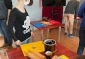 Uczestnicy Programu Rehabilitacja 25 plus wykonują pierniczki podczas warsztatów w Muzeum Regionalnym w Radomsku na stole widoczna zółte kartki z ciastem piernikowym.